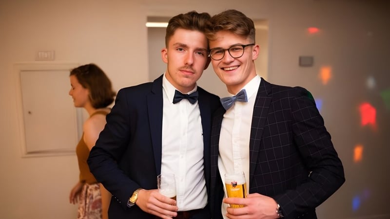 Zwei junge Männer in formeller Kleidung stehen bei einer Feier auf dem Campus der Merchiston Castle School und halten Getränke.