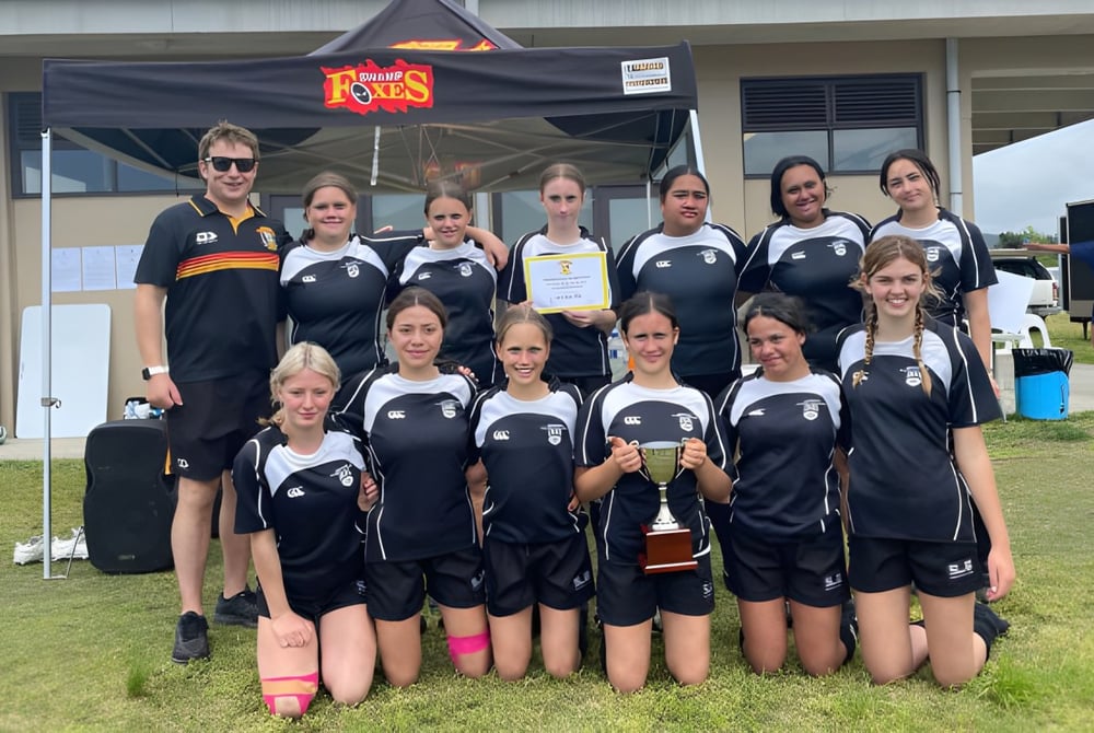 Eine Gruppe junger Athletinnen steht vor einem Zelt auf dem Sportgelände der Mercury Bay Area School.