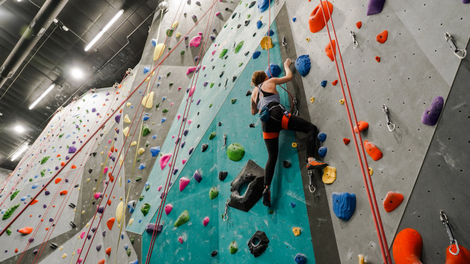 Eine Person klettert an der bunten Kletterwand in der Indoor-Anlage des Mercy College.