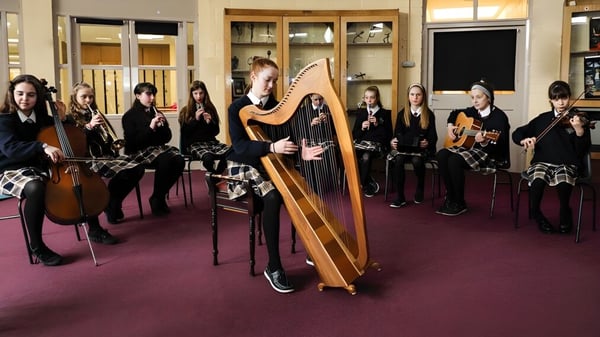 Eine Gruppe von Musikschülern, darunter eine Harfenistin, steht im Raum auf dem Campus des Mercy College.