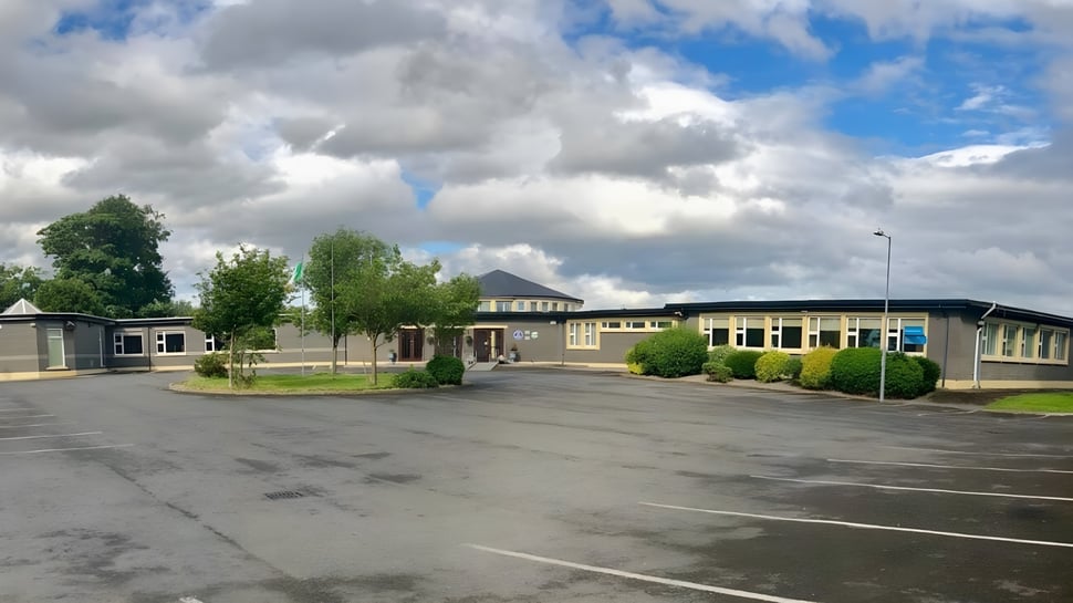 Der gepflasterte Parkplatz auf dem Gelände des Mercy College ist von Bäumen und Gebäuden bei bewölktem Himmel umgeben.
