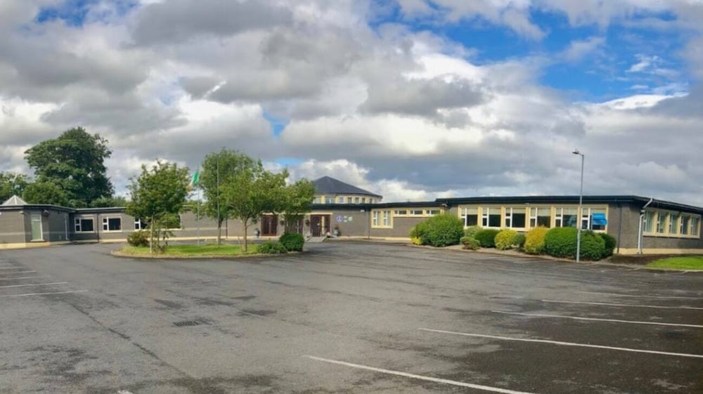 Ein gepflasterter Parkplatz auf dem Campus des Mercy College umgeben von Bäumen und Gebäuden unter bewölktem Himmel.