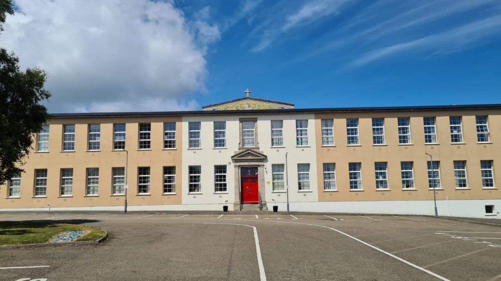 Das mehrstöckige gelbe Gebäude mit einer kreuzbekrönten Kuppel steht auf dem Gelände der Mercy Secondary School.