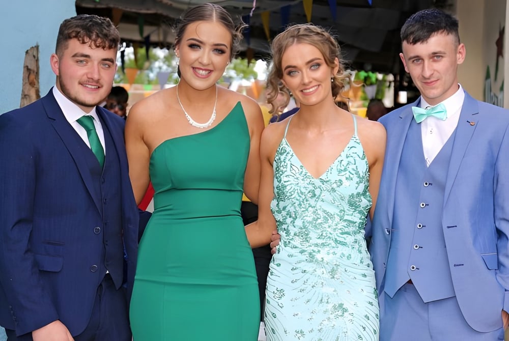 Vier Personen in festlicher Kleidung posieren auf einem Event der Mercy Secondary School.