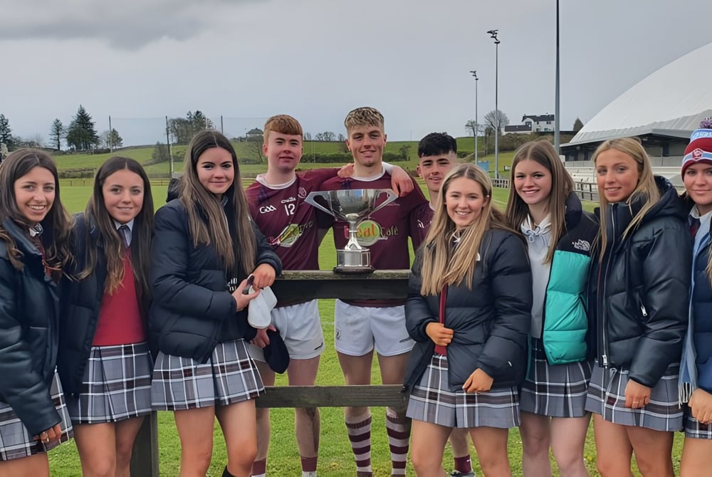 Eine Gruppe von Schülerinnen und Schülern der Mercy Secondary School hält gemeinsam draußen einen Pokal auf dem Schulgelände.