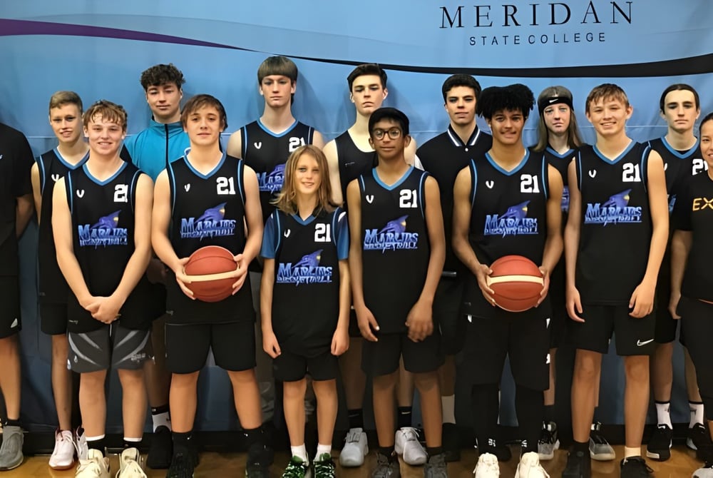 Eine Gruppe junger Basketballspielerinnen und -spieler posiert vor einem Banner des Meridan State College.