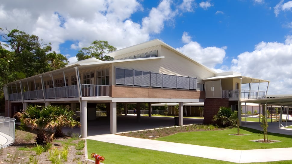 Das moderne zweistöckige Gebäude des Meridan State College ist von Palmen und grünem Gras umgeben.