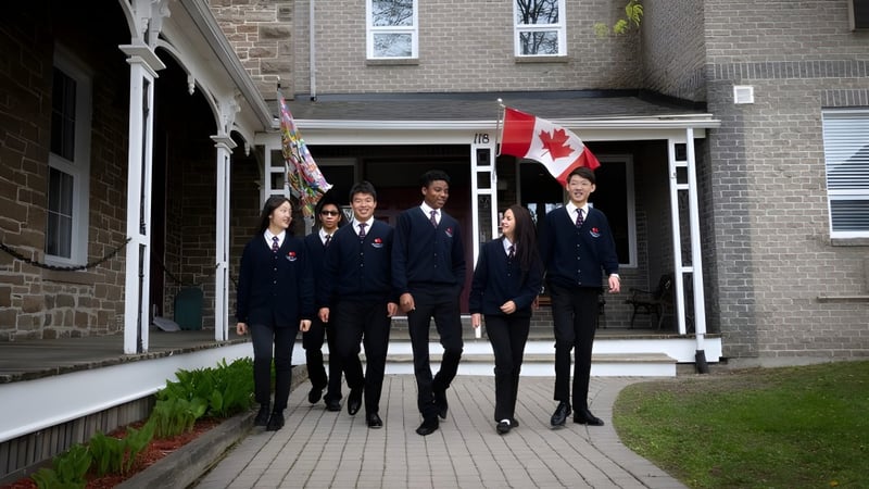 Schüler der Merrick Preparatory School in formeller Kleidung gehen gemeinsam auf einem Weg vor einem Backsteingebäude mit kanadischer Flagge.