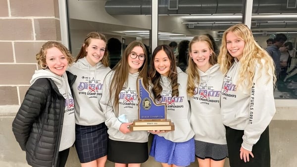 Eine Gruppe von Schülerinnen im Mesa Unified School District hält gemeinsam eine Trophäe und posiert in einer schulischen Umgebung.