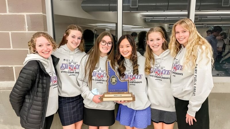 Eine Gruppe von Schülerinnen im Mesa Unified School District hält gemeinsam eine Trophäe und posiert in einer schulischen Umgebung.