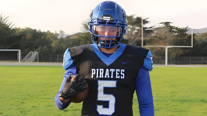 Ein Schüler des Mesa Unified School District steht im blauen Football-Trikot mit der Nummer 5 auf einem grünen Spielfeld vor einem Torpfosten.