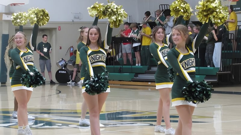 Cheerleader der Metro East Lutheran High School stehen in grün-gelben Uniformen auf dem Basketballfeld vor Zuschauern.