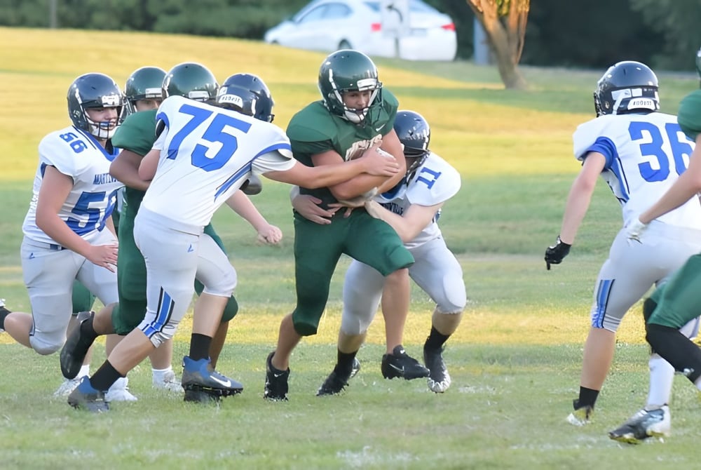 Spieler der Metro East Lutheran High School beim Footballspiel auf dem Spielfeld mit Bäumen im Hintergrund.