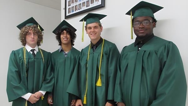 Vier Schüler in grünen Abschlussroben feiern ihren erfolgreichen Abschluss an der Metro East Lutheran High School.