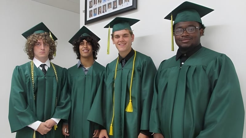 Vier Schüler in grünen Abschlussroben feiern ihren erfolgreichen Abschluss an der Metro East Lutheran High School.