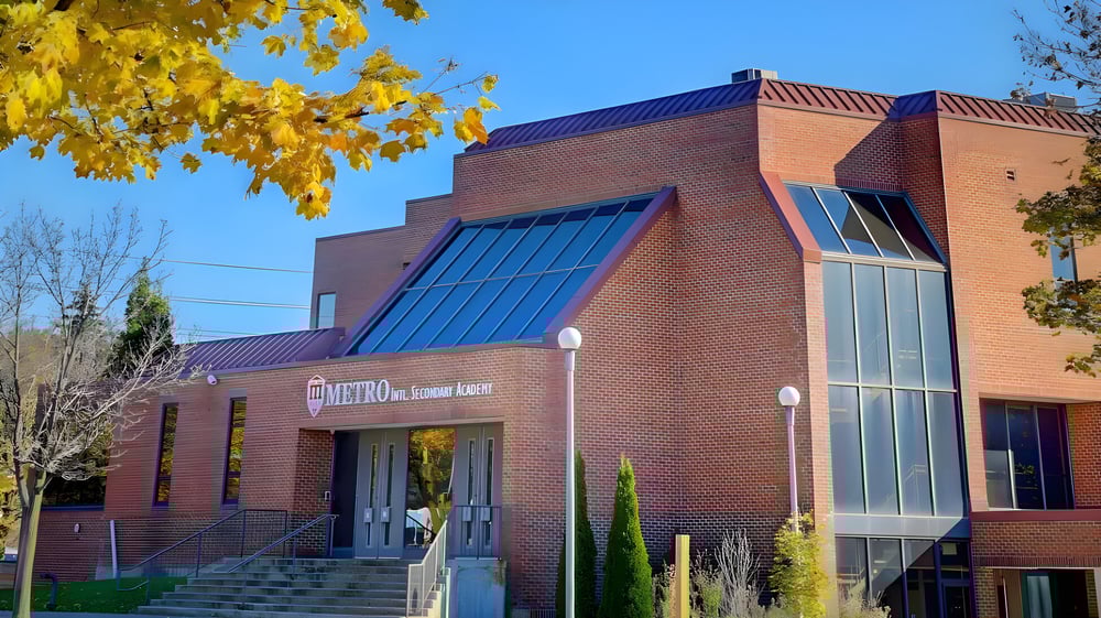 Das Backsteingebäude der Metro International Secondary Academy ist von gelbem Herbstlaub umgeben.