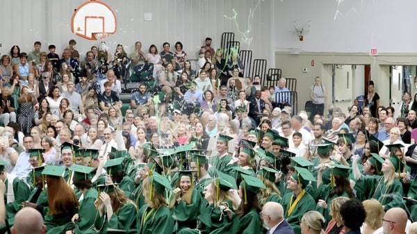 Absolventinnen und Absolventen der Metro International Secondary Academy sitzen in grünen Talaren in einer Aula während der Abschlussfeier.