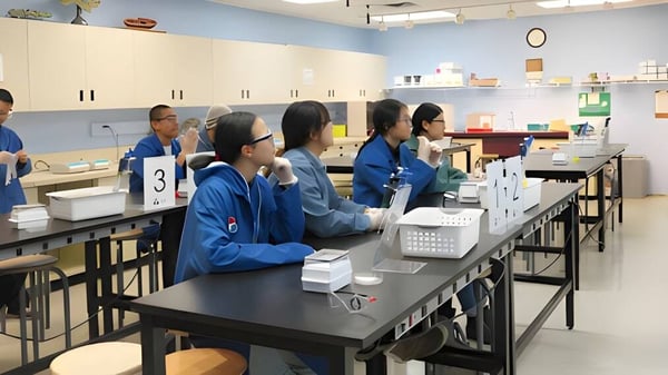 Schüler der Metro International Secondary Academy sitzen im Klassenzimmer an Tischen mit Unterrichtsmaterialien.