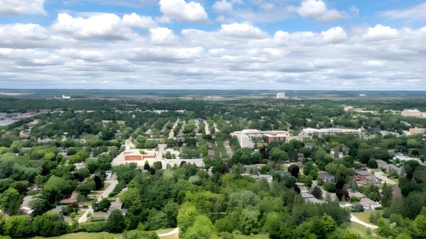 Eine grüne Landschaft mit Blick auf eine große Stadt unter bewölktem Himmel bei der Metro International Secondary Academy.