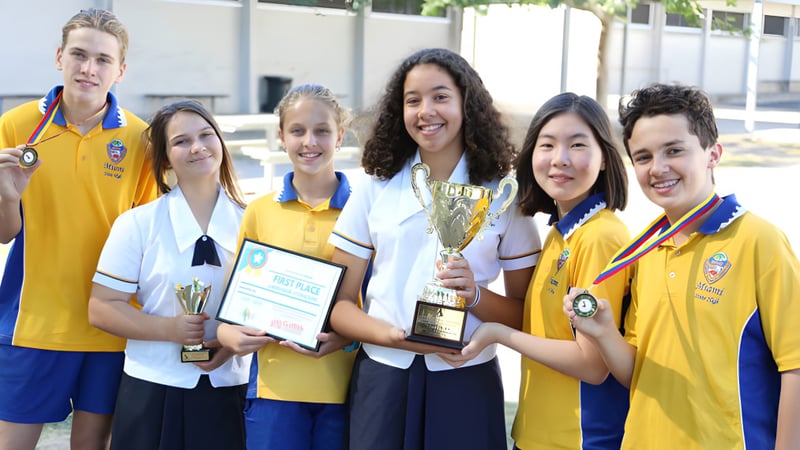 Schüler der Miami State High School feiern mit Trophäen und Urkunden ihre Erfolge im Schulumfeld.