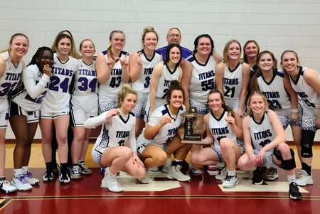 Schülerinnen der Michigan Lutheran High School feiern auf dem Basketballfeld ihren Sieg mit einem Pokal.