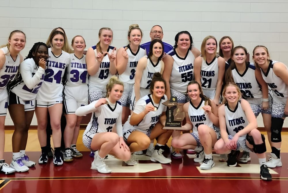Schülerinnen der Michigan Lutheran High School feiern auf dem Basketballfeld ihren Sieg mit einem Pokal.