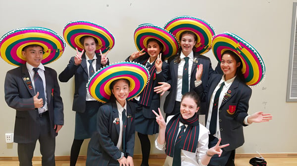 Eine Gruppe von Schülerinnen und Schülern der Middleton Grange School posiert zusammen mit bunten Hüten und Anzügen vor einem neutralen Hintergrund.