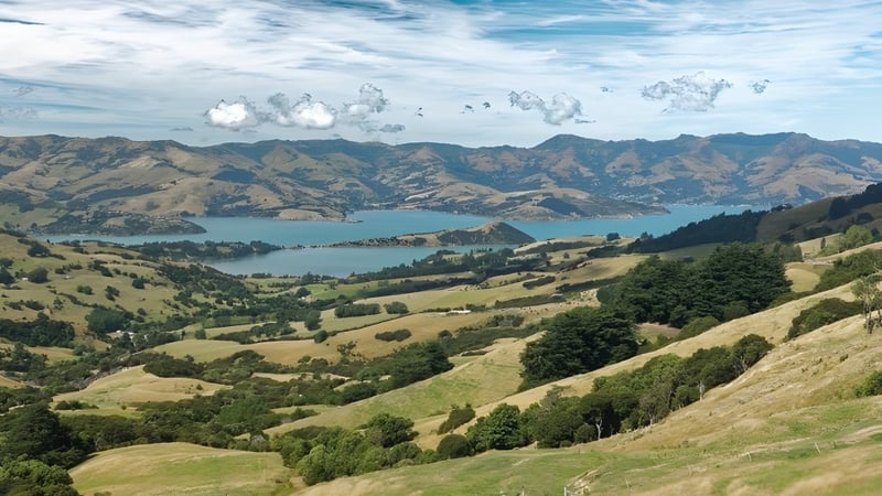 Landschaft mit Hügeln, See und Bergen unter bewölktem Himmel nahe der Middleton Grange School.