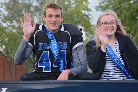 Zwei Schüler der Middletown Christian School sitzen auf einer Bank im Freien und winken in die Kamera.