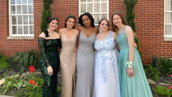 Eine Gruppe von fünf Schülerinnen der Middletown Christian School steht vor einem Backsteingebäude mit grünem Hintergrund.