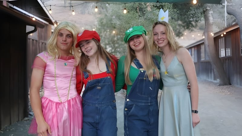 Vier Schülerinnen in bunten Kostümen stehen zusammen im Freien auf dem Campus der Midland School.