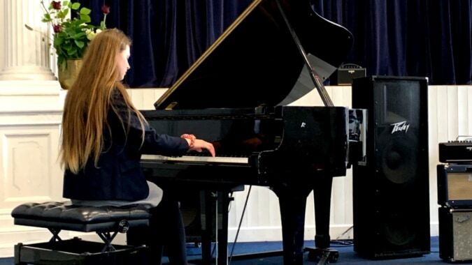 Eine Schülerin spielt Klavier auf der Bühne im Auditorium des Midleton College.