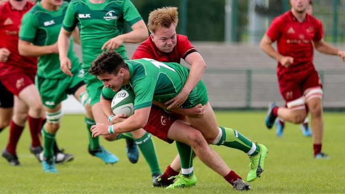 Schüler von Midleton College führen während eines Rugbyspiels auf dem Spielfeld einen Tackle aus.