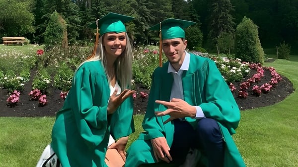 Zwei Schüler in grünen Abschlusskleidern stehen im Garten auf dem Campus der Miles Macdonell Collegiate.