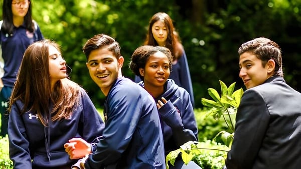 Schüler der Mill Hill International stehen gemeinsam in einer grünen Außenanlage.
