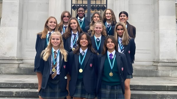 Eine Gruppe Schüler steht auf der Treppe vor dem repräsentativen Gebäude der Mill Hill School und trägt Medaillen.