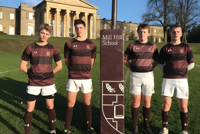 Eine Gruppe Schüler in Sportuniformen steht vor dem Schulgebäude der Mill Hill School.