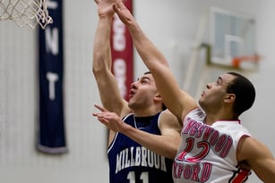 Zwei Schüler der Millbrook School kämpfen um den Ball an einem Basketballkorb in der Turnhalle.