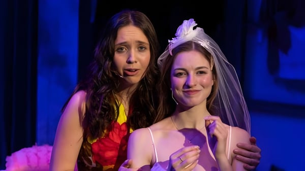 Zwei Frauen stehen zusammen auf einer Bühne mit blauem Hintergrund auf dem Campus der Millbrook School.