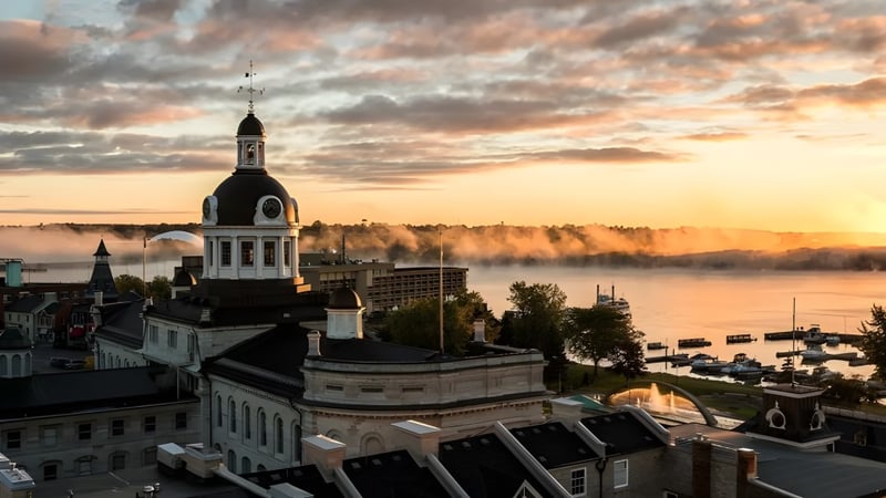 Der historische Kirchturm ist bei Sonnenuntergang von der École secondaire publique Mille-îles aus über einem nebligen Fluss zu sehen.
