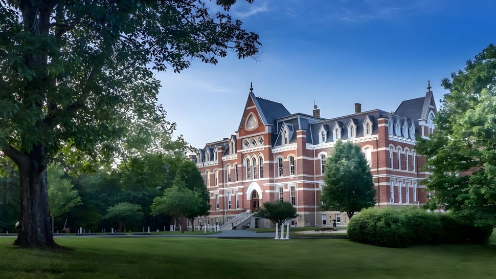 Das Gebäude der Miller School of Albemarle steht eingebettet in eine grüne Landschaft mit Bäumen und gepflegtem Rasen.