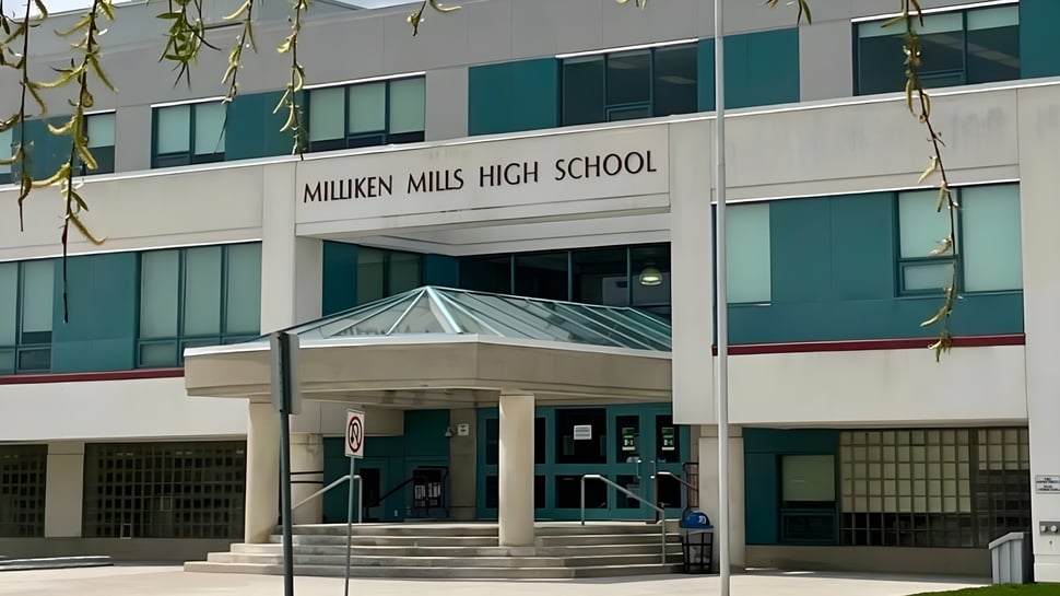 Der Eingang des modernen Gebäudes der Milliken Mills Secondary School ist mit Glas und Beton gestaltet und von hängenden Pflanzen umgeben.
