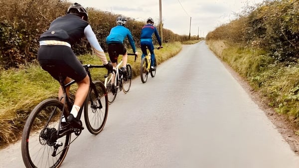 Eine Gruppe von Schülern der Milton Abbey School fährt mit Fahrrädern auf einem gepflasterten Weg durch die Landschaft.