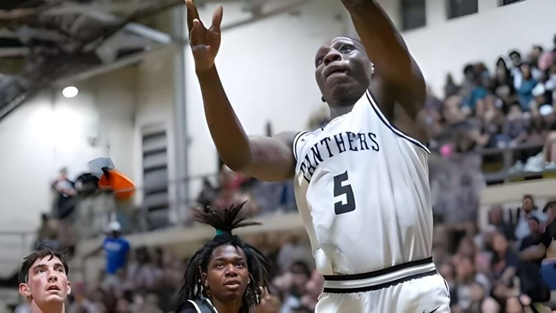 Ein Basketballspieler der Milton District High School springt mit erhobenen Armen während eines Spiels.