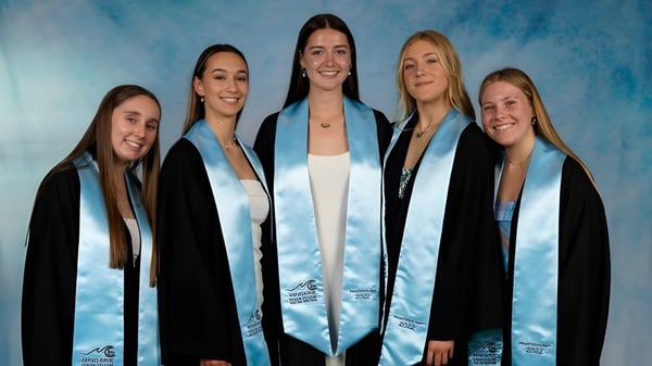 Fünf Schülerinnen in schwarzen Abschlussroben stehen vor einem blauen Hintergrund am Mindarie Senior College.