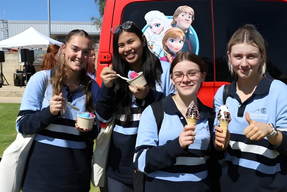 Eine Gruppe Schülerinnen der Mindarie Senior College posiert vor einem roten Fahrzeug mit Disney-Motiv bei einer Außenveranstaltung.
