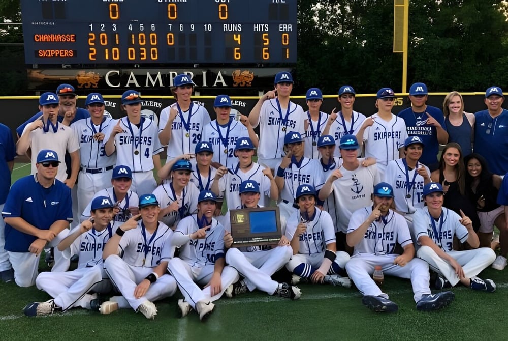 Eine Gruppe von Baseballspielerinnen und Baseballspielern posiert auf dem Baseballfeld der Minnetonka Public Schools vor der Anzeigetafel.