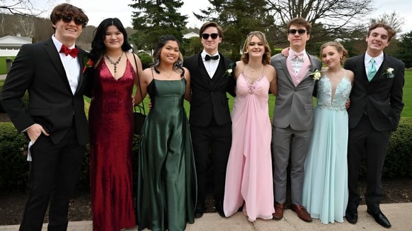 Eine Gruppe von Personen steht formell vor Bäumen und einem Pavillon auf dem Gelände der Miramichi Valley High School.