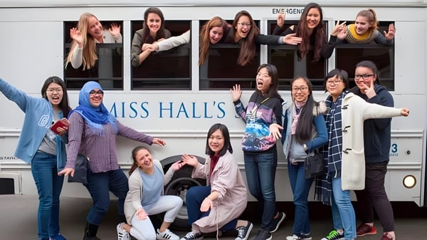 Eine Gruppe Schülerinnen posiert vor einem Bus mit der Aufschrift Miss Hall's School.