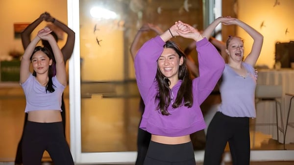 Drei Schülerinnen der Miss Porter's School führen in einem Studio Yoga-Übungen mit erhobenen Armen aus.